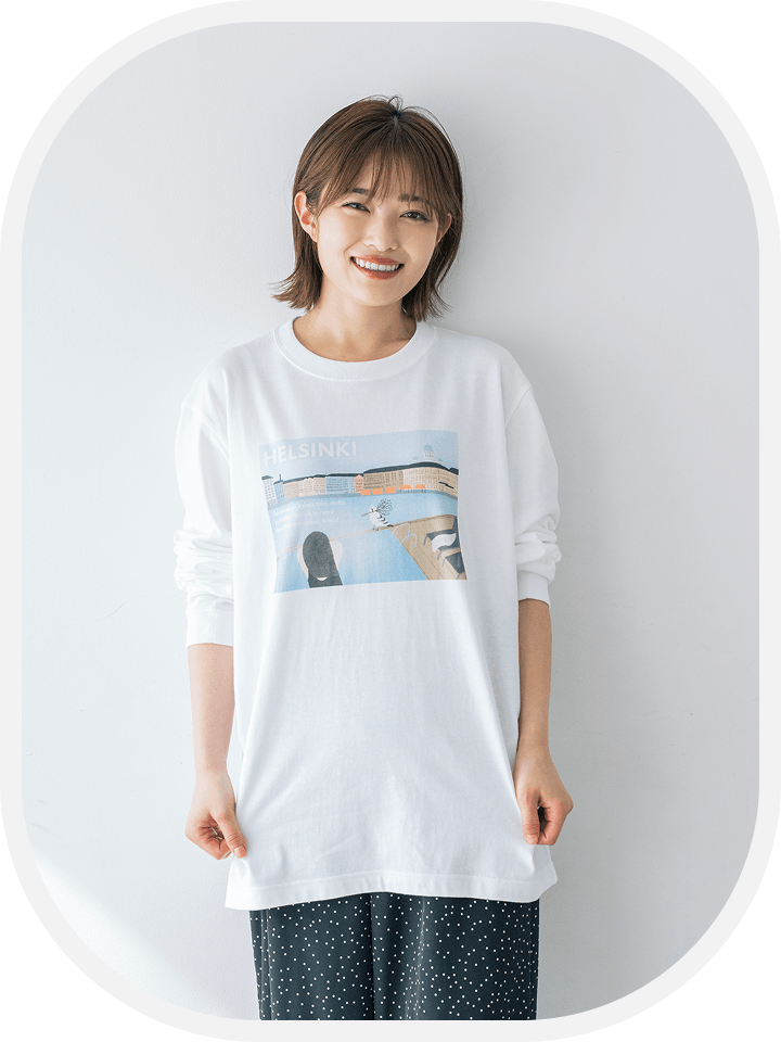 【商品写真】中央に「Sauna ja kaupunkinäkymä」のイラストがデザインされている白いロング長袖Tシャツを着用している、井上さん