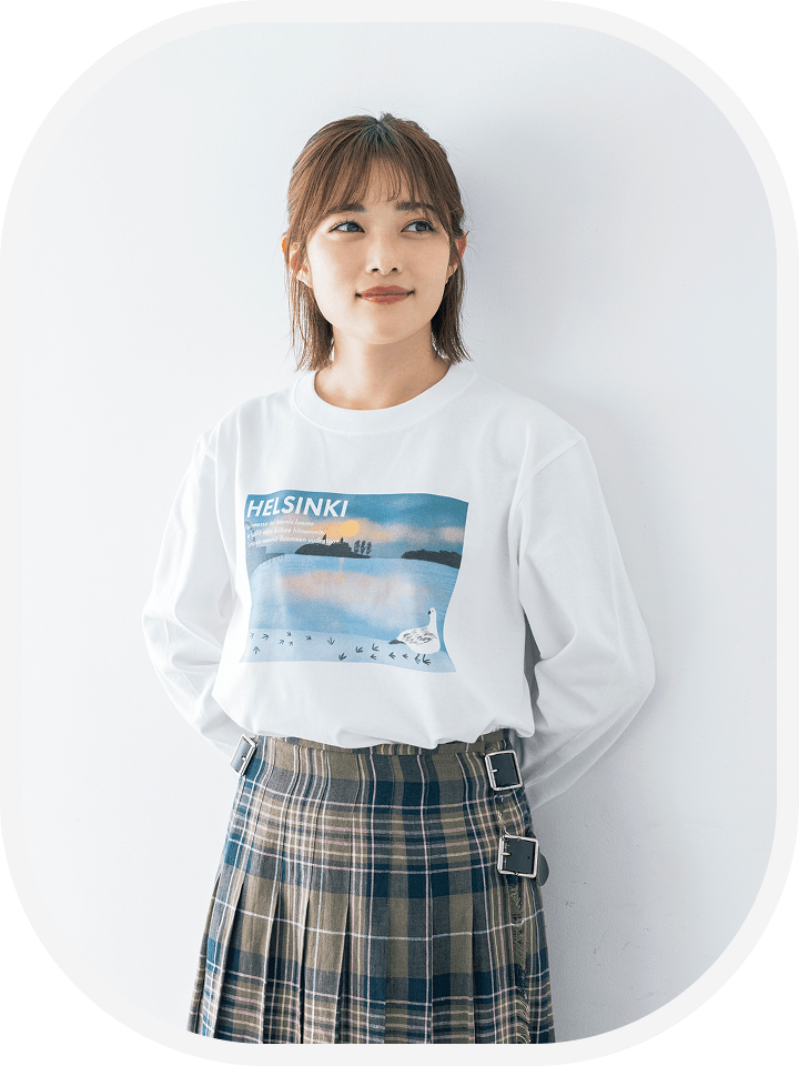【商品写真】中央に「Auringonnousu」のイラストがデザインされている白いロング長袖Tシャツを着用している、井上さん