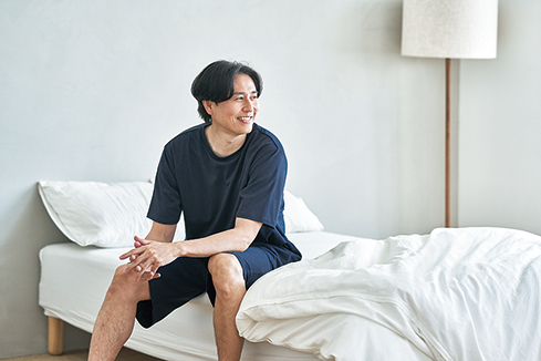 ベッドサイドでRecoverypro Lab.の疲労回復ウェアを着用する男性